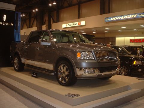 1999 Ford Crown Victoria - A gray Lincoln Mark LT pickup truck is displayed at an auto show, with other vehicles and signage visible in the background.
