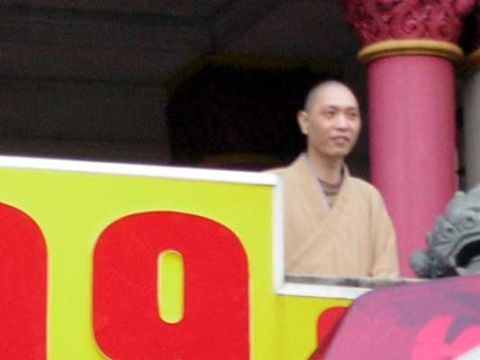 1995 Ford Bronco - Man in monk robes stands behind a colorful sign with large red letters.