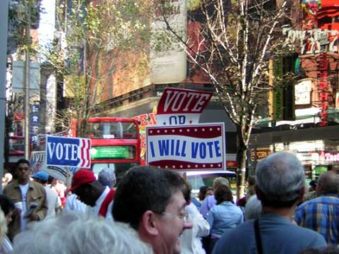 1995 Ford Bronco - A crowd of people are seen on a city street holding signs related to voting, with a bus in the background.
