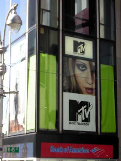 1995 Ford Bronco - A building facade displays an MTV advertisement a person's face and logos, with a Bank of America sign at the bottom.