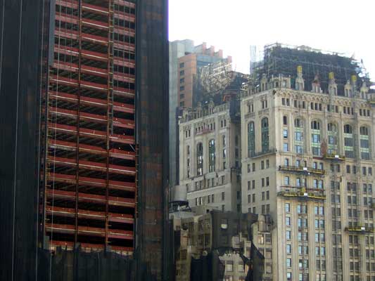 Construction site with scaffolding on buildings and a partially covered skyscraper