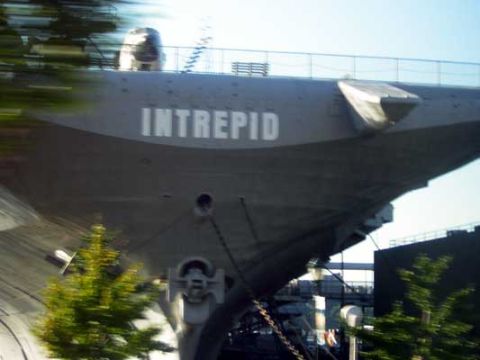 1995 Ford Bronco - The USS Intrepid aircraft carrier is docked, with the name 'INTREPID' clearly visible on its hull.