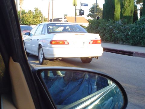1993 Ford Taurus - A white sedan with dual exhaust pipes is viewed from the rear, with a Ford emblem visible on its trunk.