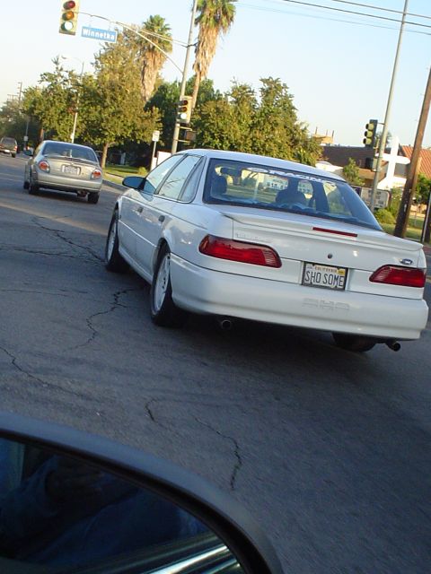 1993 Ford Taurus - Rear view of a white 1993 Ford Taurus SHO on the road, with a custom license plate.
