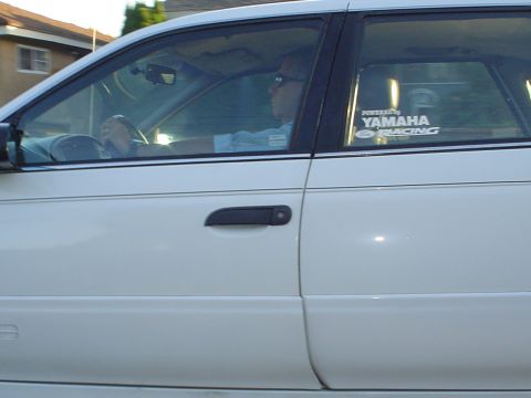 1993 Ford Taurus - Side view of a white sedan's interior, showing the driver and a Yamaha Racing sticker on the window.