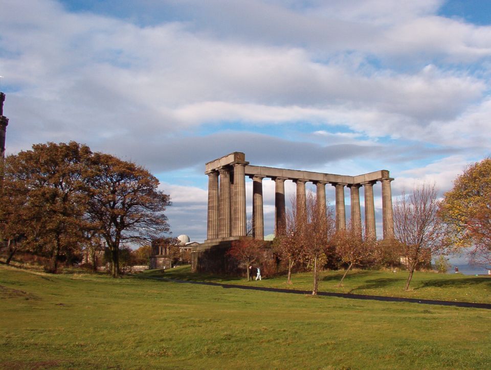 Unfinished stone columns of a monument on a grassy hill under blue sky