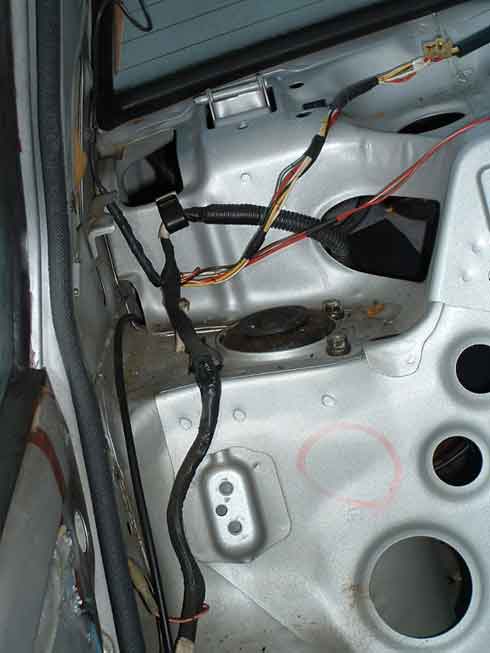Stripped, silver-painted rear interior showing right rear strut tower top and wiring harness