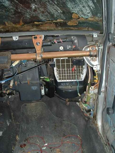 1986 Toyota Corolla - Disassembled car interior reveals the HVAC system and exposed wiring beneath a damaged windshield.