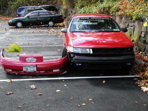 1992 Ford Taurus - 1992 Ford Taurus front bumper removed after an incident. Another vehicle is visible in the background.