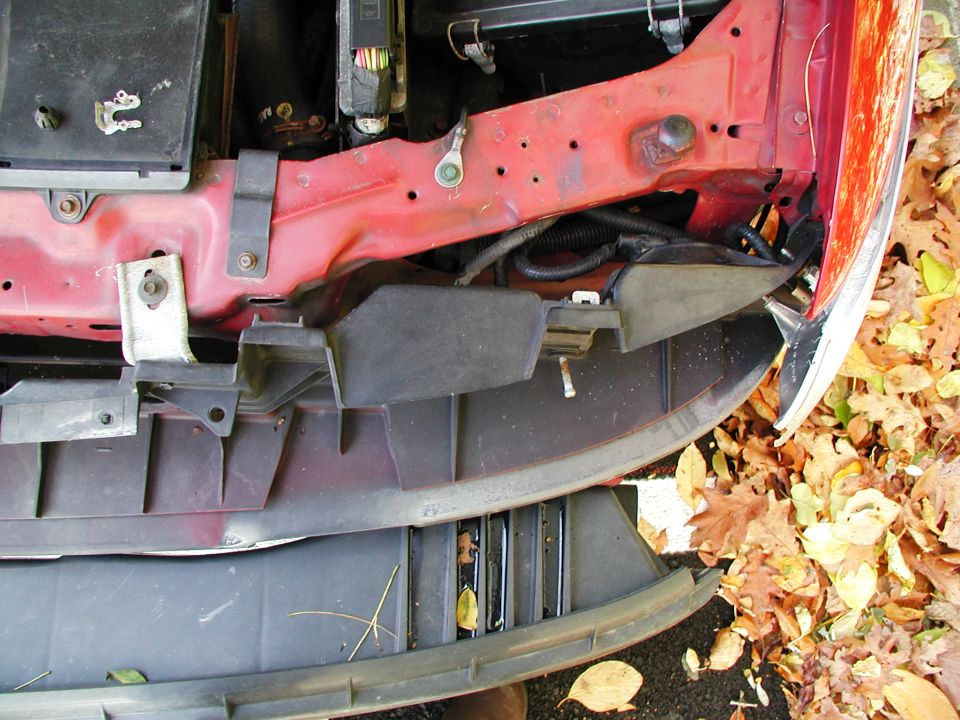 Red fender and black bumper assembly with autumn leaves on the ground