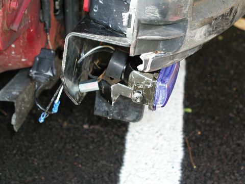 1992 Ford Taurus - The front corner of a vehicle shows damage to the bumper and headlight, with exposed wiring and a detached turn signal.