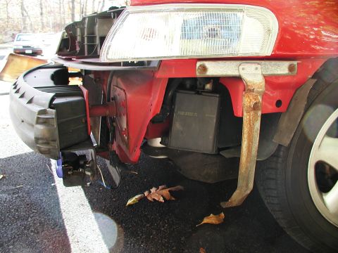 1992 Ford Taurus - The front end of a red 1992 Ford Taurus shows damage to the bumper and headlight assembly.