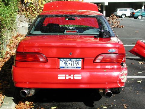 1992 Ford Taurus - 1992 Ford Taurus SHO shows significant damage to its rear bumper and taillight assembly.