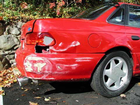 1992 Ford Taurus - Rear view of a red 1992 Ford Taurus showing significant damage to the bumper and taillight.