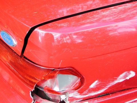 1992 Ford Taurus - Damage to the rear of a red 1992 Ford Taurus, showing a broken taillight and dented trunk.
