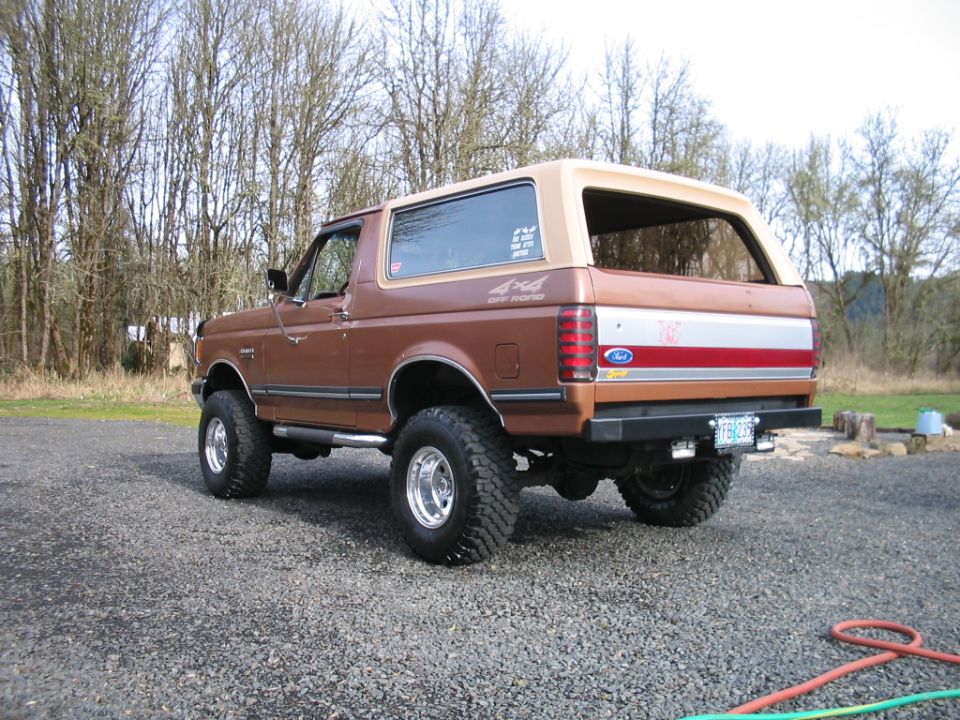 Brown Ford Bronco parked on gravel, trees in background. Has 4x4 Off Road decal on side