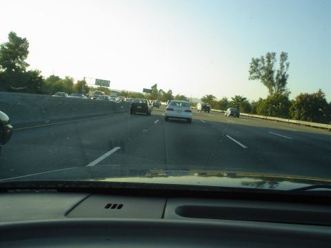 1993 Ford Taurus - A white 1993 Ford Taurus drives on a sunny highway alongside other vehicles.
