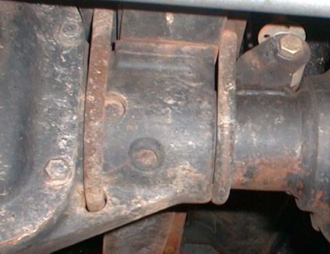 1990 Ford Bronco - Close-up of a rusty rear axle housing and suspension bracket, with Supermotors.net logo.