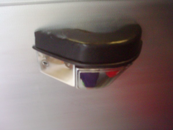 Close-up of a vehicle door handle and lock mechanism with a black grip and chrome trim