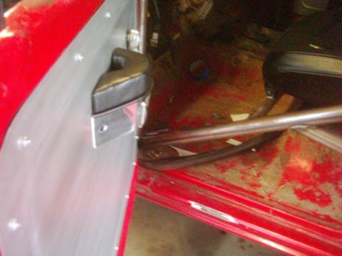 1978 Ford Bronco - Close-up of the interior door panel and roll cage in a red vehicle.