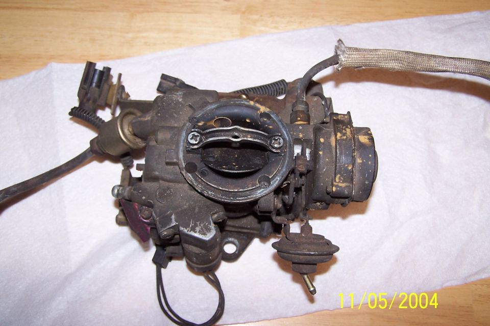 Close-up of a dirty carburetor with wires and hoses attached