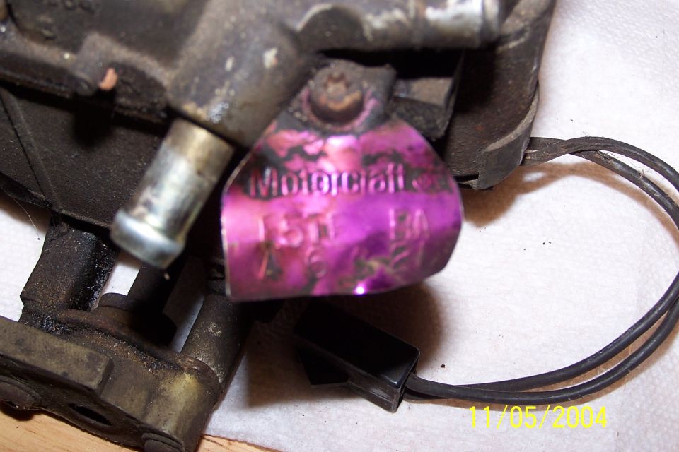 Motorcraft carburetor tag with purple tint and stamped numbers