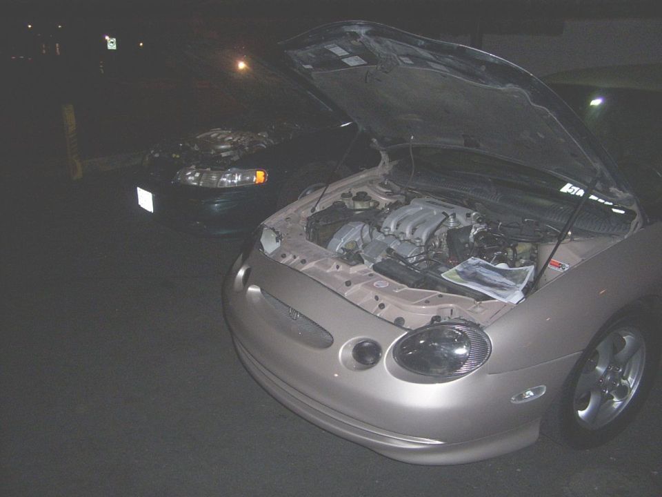 1998 Mercury Sable and another car, both with hoods open at night