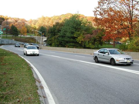 1992 Ford Taurus - A silver sedan travels on a highway surrounded by trees in fall colors.