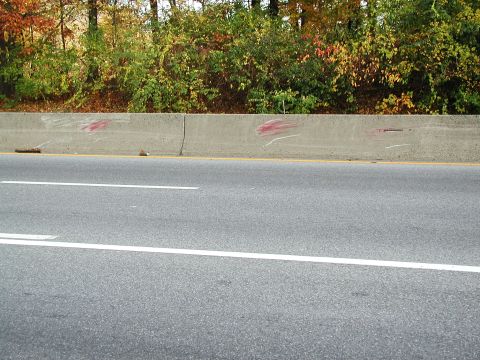 1992 Ford Taurus - A concrete barrier on the side of a highway with trees and foliage visible behind it.