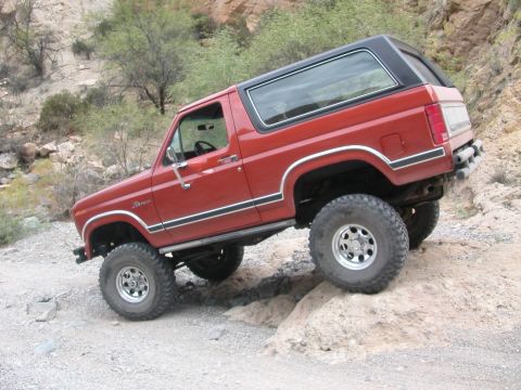 1984 Ford Bronco - 1984 Ford Bronco tackling a challenging off-road trail with significant articulation.