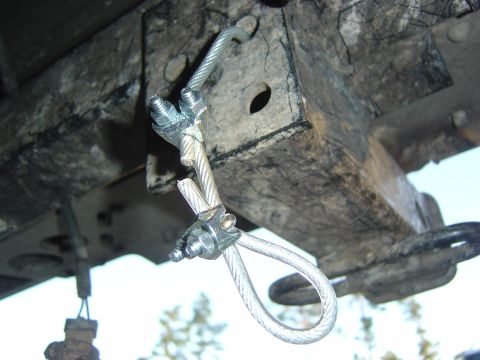 1993 Ford Bronco - Close-up of a frayed cable attached to the undercarriage of a vehicle, indicating potential wear and tear.