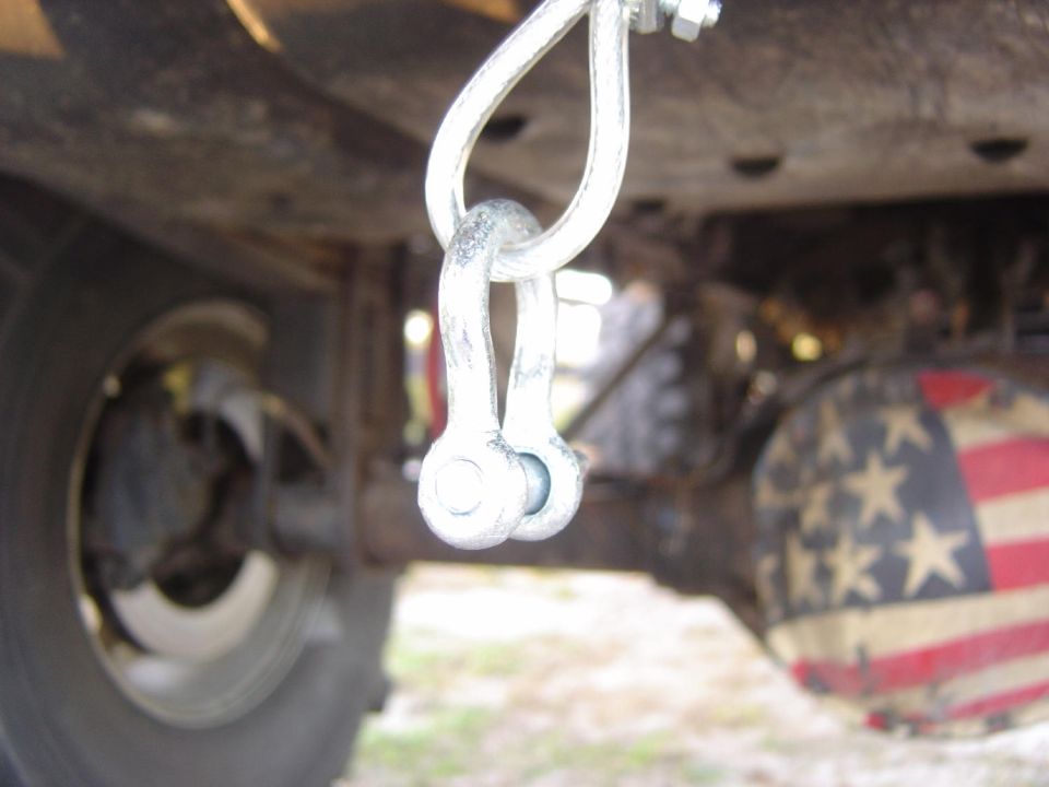 Undercarriage view of a vehicle showing a shackle attached to a frame, with a differential cover painted like the American flag