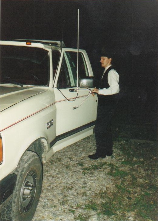 Person standing by the open door of a white 1987 Ford F-150 truck