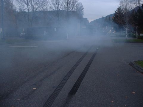 1999 Ford Crown Victoria - Tire marks and smoke on asphalt indicate a vehicle performed a burnout.