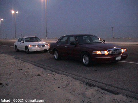 2000 Ford Crown Victoria - Two Ford Crown Victorias are seen on a highway during twilight hours.