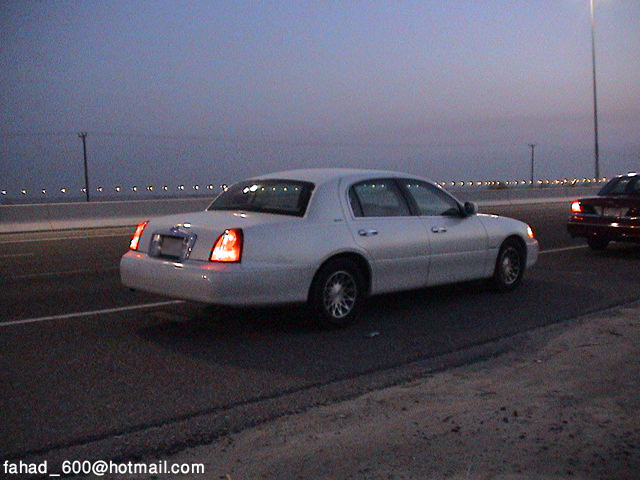 White sedan with illuminated taillights, seen from the rear quarter