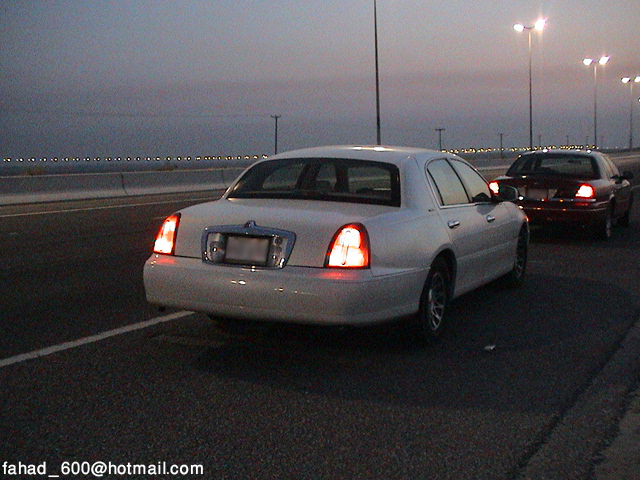 White sedan's rear view at dusk with another car behind it