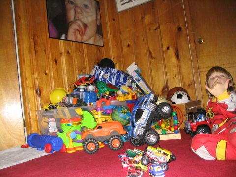 1986 Ford Bronco - A child sits amongst a large collection of toys, including several toy vehicles.
