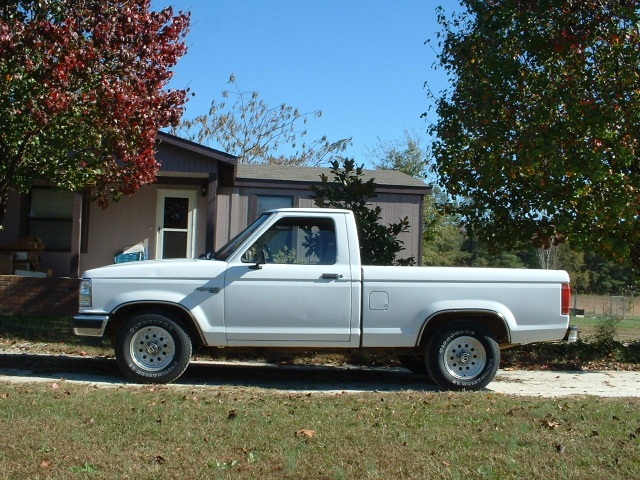 White Ford Ranger regular cab pickup parked side-on in front of a house