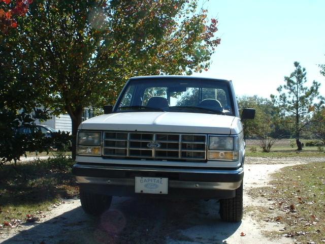 White Ford Ranger pickup from the front with a Capital Ford dealer plate, parked on a dirt driveway