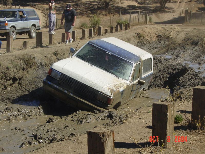 1990 Ford Bronco stuck in mud pit with another Bronco in background