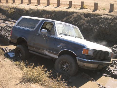 1990 Ford Bronco - This 1990 Ford Bronco is stuck in a muddy ditch, with its tires partially submerged.