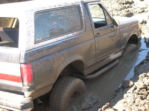 1990 Ford Bronco - This Ford Bronco is deeply stuck in mud, with its tires submerged.