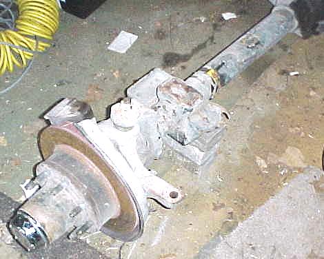 1984 Ford Bronco - A close-up view of a front axle assembly, including the brake rotor and hub, is shown on a concrete floor.