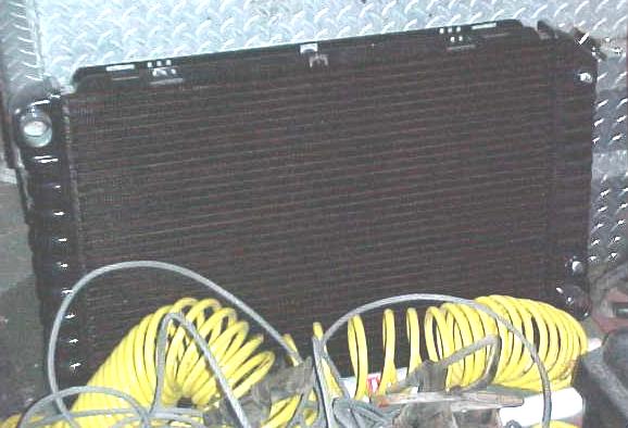 Radiator standing on diamond-plate floor with coiled yellow air line below it