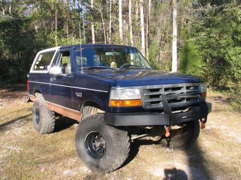 1995 Ford Bronco - This lifted Ford Bronco sits in a grassy area surrounded by trees, its off-road modifications.