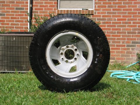 1995 Ford Bronco - A single tire and wheel assembly is shown resting on grass.