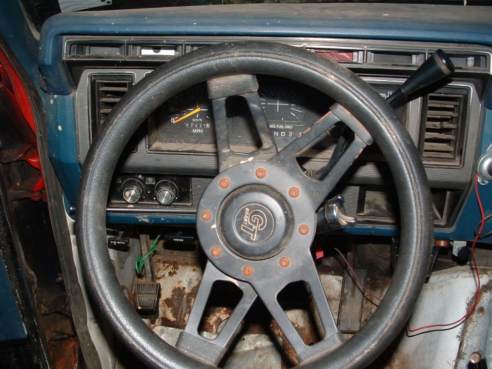 Aftermarket GT steering wheel and worn blue dashboard in a truck interior