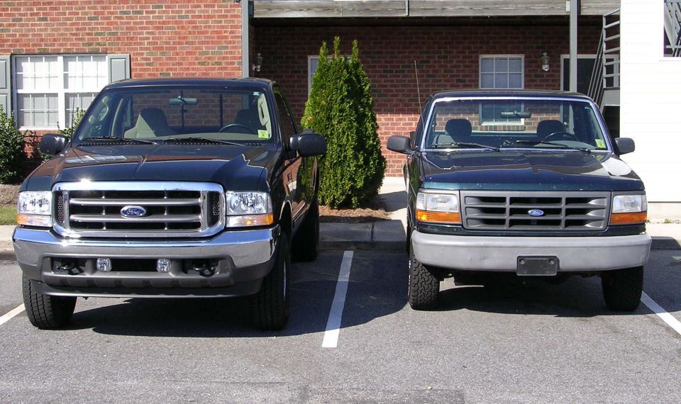 Black Ford Super Duty and older Ford F-series pickup parked side by side