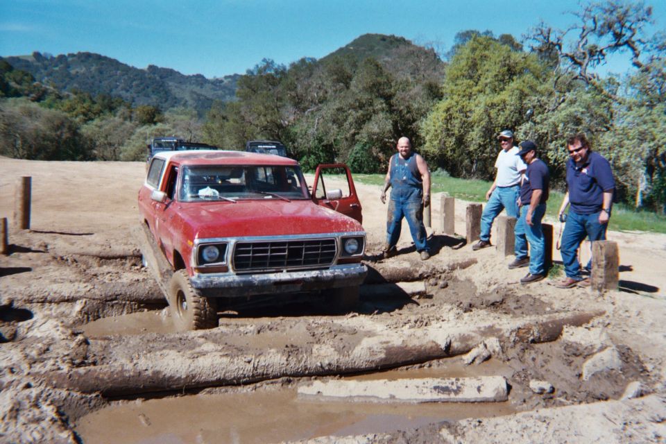 red SUV stuck in mud pit, guys watching